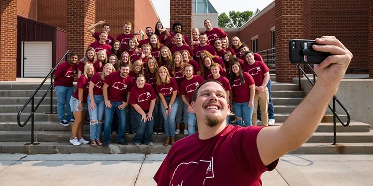 A photo of the Associate director of housing taking a selfie with his staff at CSC